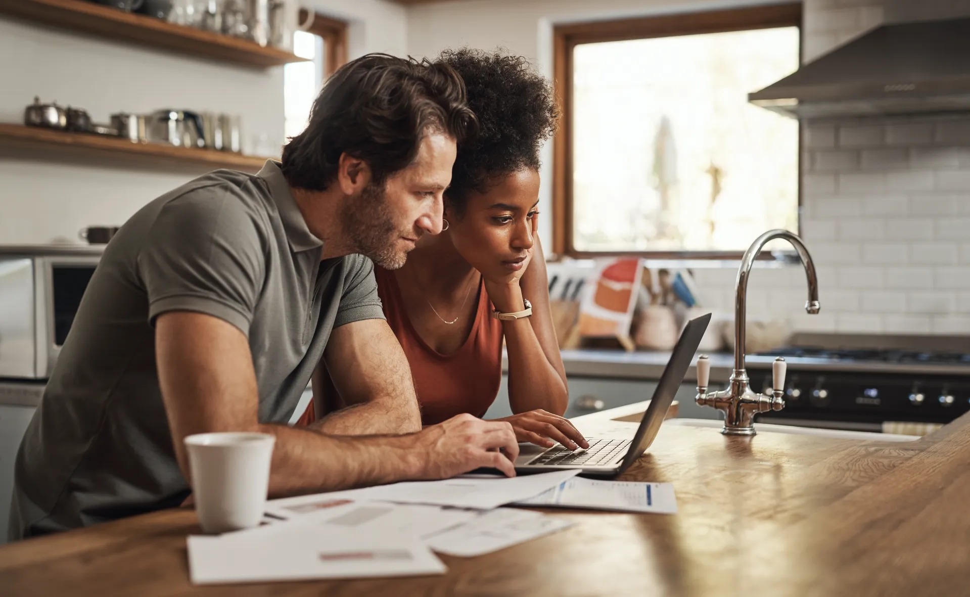 Couple reviewing mortgage documents on a laptop at their kitchen counter